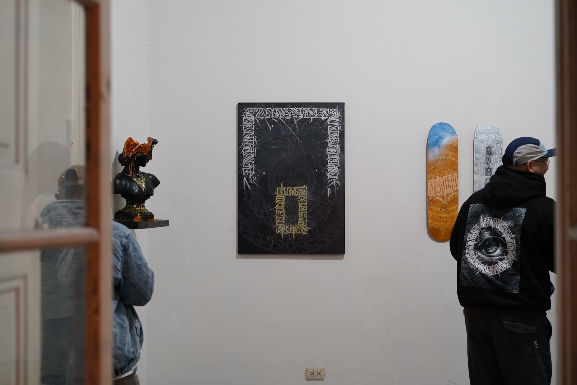 Pared de la galería con obras y skates expuestos durante Manifiesto