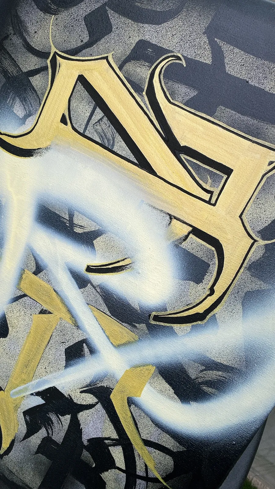 Detalle de un lienzo con caligrafía dorada y trazos blancos sobre negro